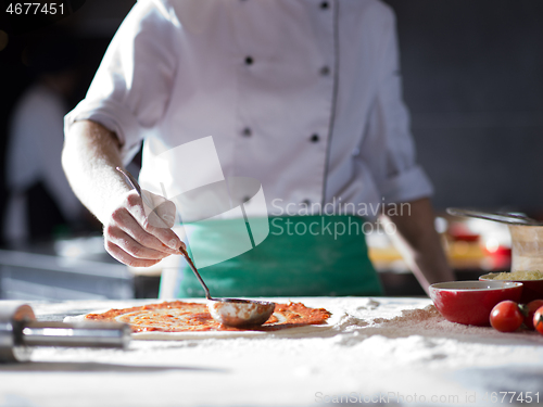 Image of Chef smearing pizza dough with ketchup