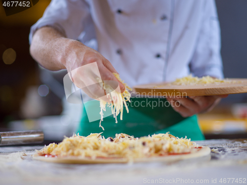 Image of chef sprinkling cheese over fresh pizza dough