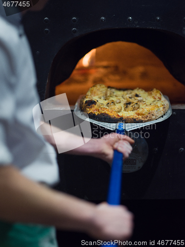 Image of chef removing hot pizza from stove