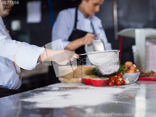 Image of chef sprinkling flour over fresh pizza dough