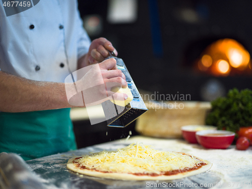 Image of chef sprinkling cheese over fresh pizza dough