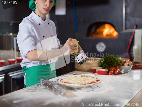 Image of chef sprinkling cheese over fresh pizza dough