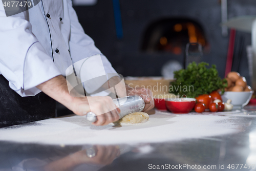 Image of chef preparing dough for pizza with rolling pin