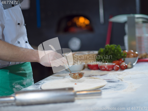 Image of chef putting cut sausage or ham on pizza dough