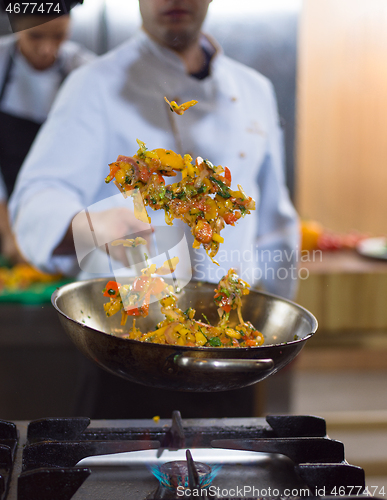 Image of chef flipping vegetables in wok