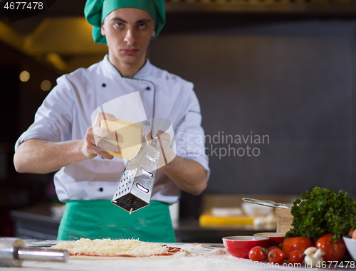 Image of chef sprinkling cheese over fresh pizza dough