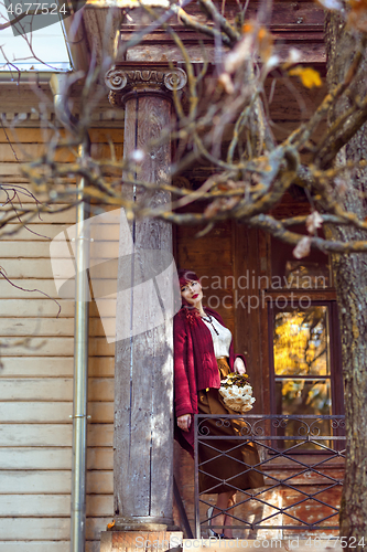 Image of Girl standing on old house balcony