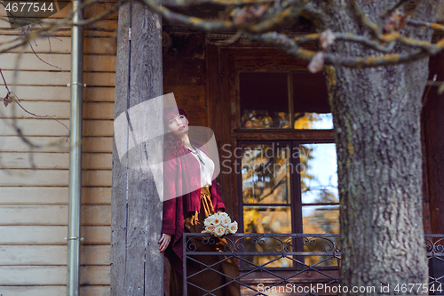 Image of Girl standing on old house balcony