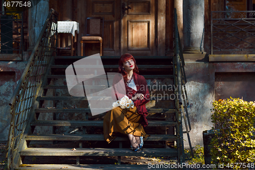 Image of Girl sitting on old house stairs