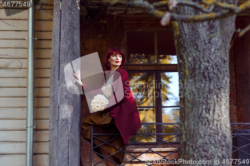 Image of Girl sitting on old house balcony