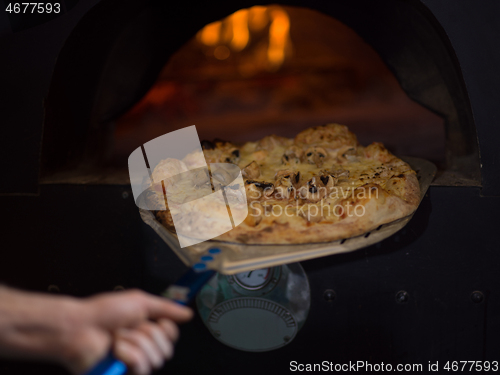 Image of chef removing hot pizza from stove