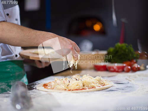 Image of chef sprinkling cheese over fresh pizza dough