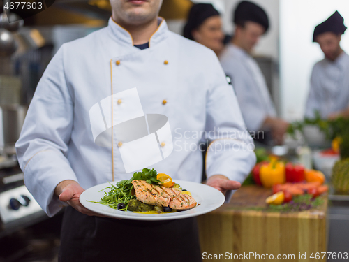 Image of Chef holding dish of fried Salmon fish fillet