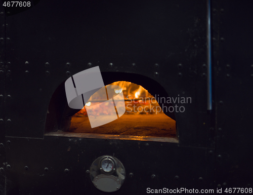 Image of chef putting delicious pizza to brick wood oven