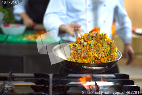 Image of chef flipping vegetables in wok