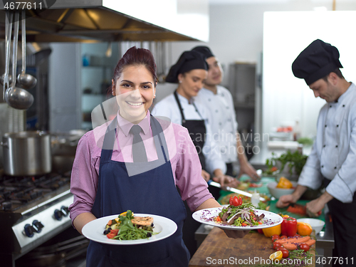 Image of young waitress showing dishes of tasty meals