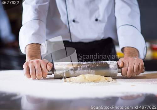 Image of chef preparing dough for pizza with rolling pin