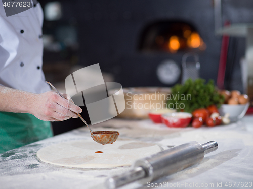 Image of Chef smearing pizza dough with ketchup