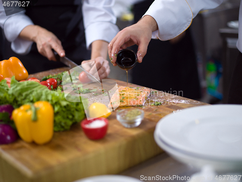 Image of Chef hands preparing marinated Salmon fish