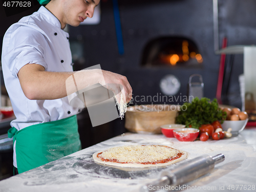 Image of chef sprinkling cheese over fresh pizza dough