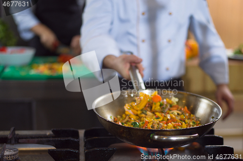 Image of chef flipping vegetables in wok