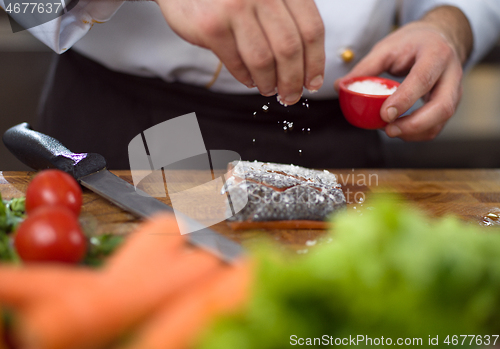 Image of Chef hands preparing marinated Salmon fish