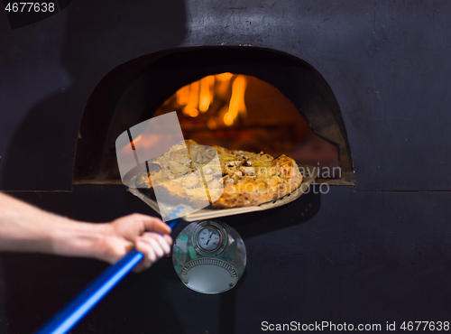 Image of chef removing hot pizza from stove