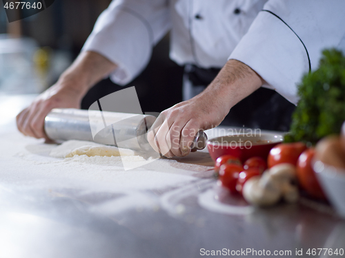 Image of chef preparing dough for pizza with rolling pin