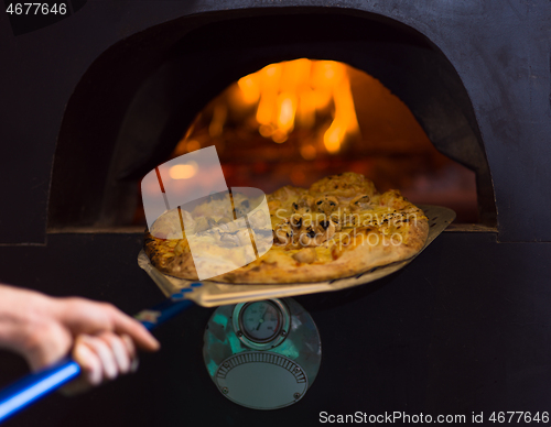 Image of chef removing hot pizza from stove