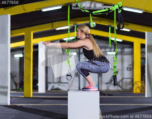 Image of woman working out  jumping on fit box