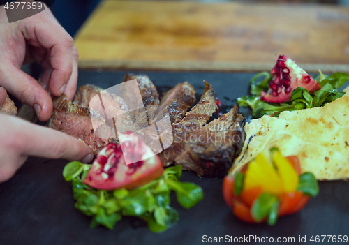 Image of closeup of Chef hands serving beef steak