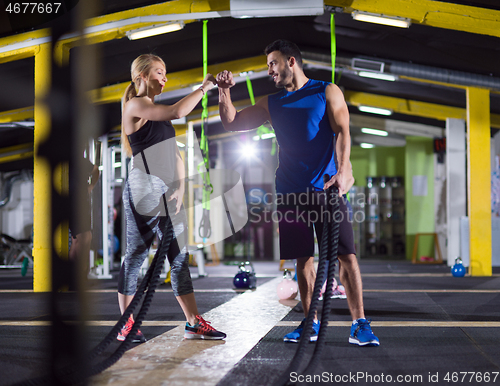 Image of sports couple doing battle ropes crossfitness exercise