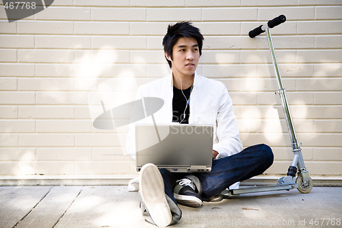 Image of Young casual asian man with laptop