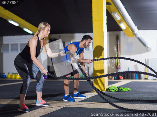 Image of sports couple doing battle ropes crossfitness exercise