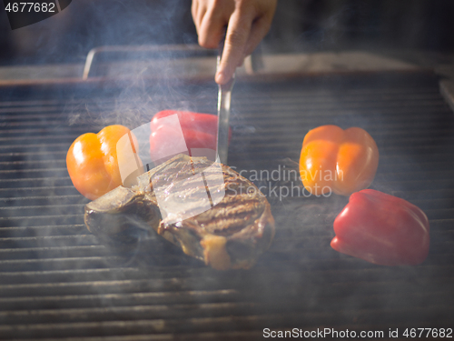 Image of chef cooking steak with vegetables on a barbecue