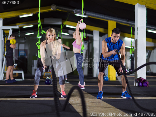 Image of sports couple doing battle ropes crossfitness exercise