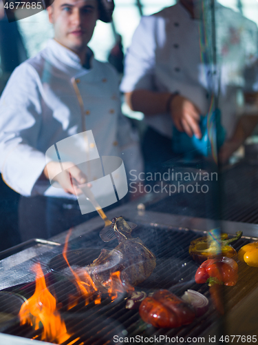 Image of chef cooking steak with vegetables on a barbecue