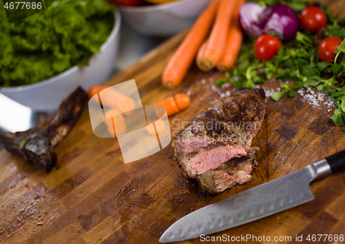 Image of Juicy slices of grilled steak on wooden board