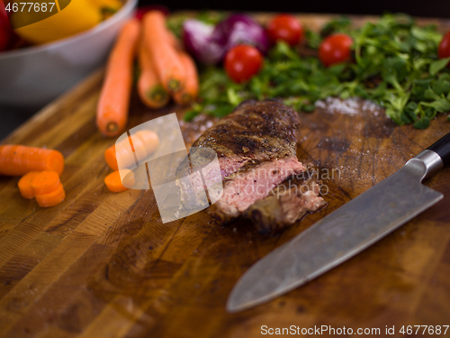 Image of Juicy slices of grilled steak on wooden board