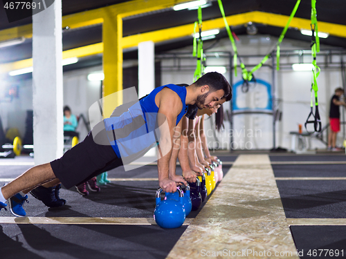 Image of young athletes doing pushups with kettlebells