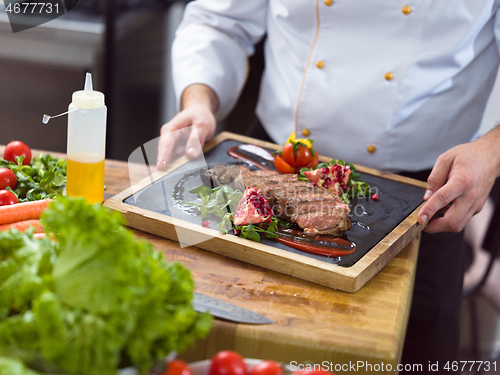 Image of closeup of Chef hands serving beef steak