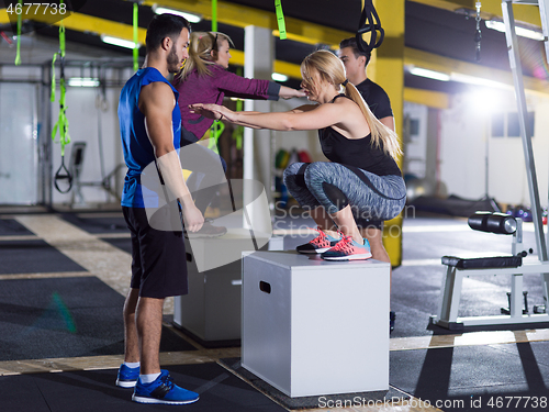 Image of athletes working out  jumping on fit box