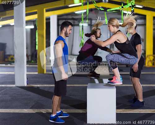 Image of athletes working out  jumping on fit box