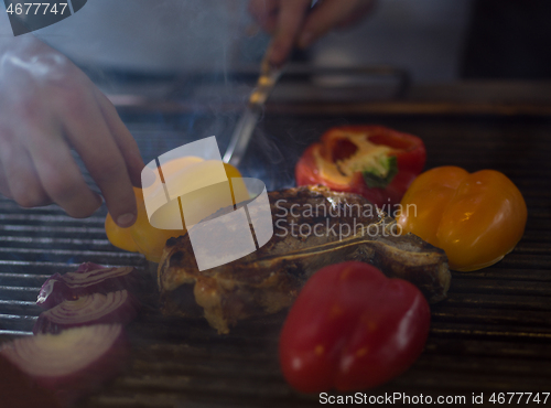 Image of chef cooking steak with vegetables on a barbecue