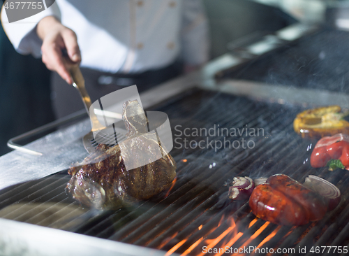 Image of chef cooking steak with vegetables on a barbecue