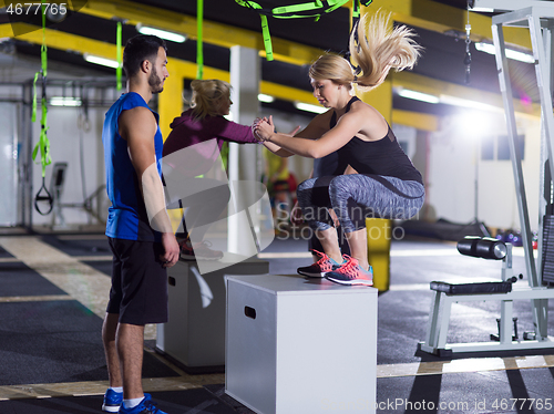 Image of athletes working out  jumping on fit box