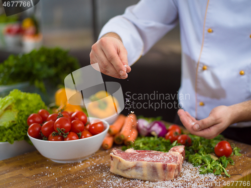 Image of Chef putting salt on juicy slice of raw steak