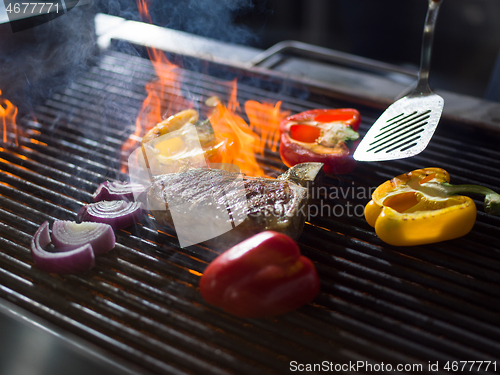 Image of chef cooking steak with vegetables on a barbecue