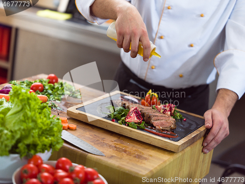 Image of Chef finishing steak meat plate