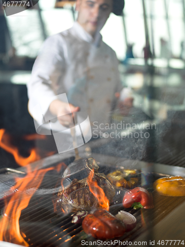 Image of chef cooking steak with vegetables on a barbecue